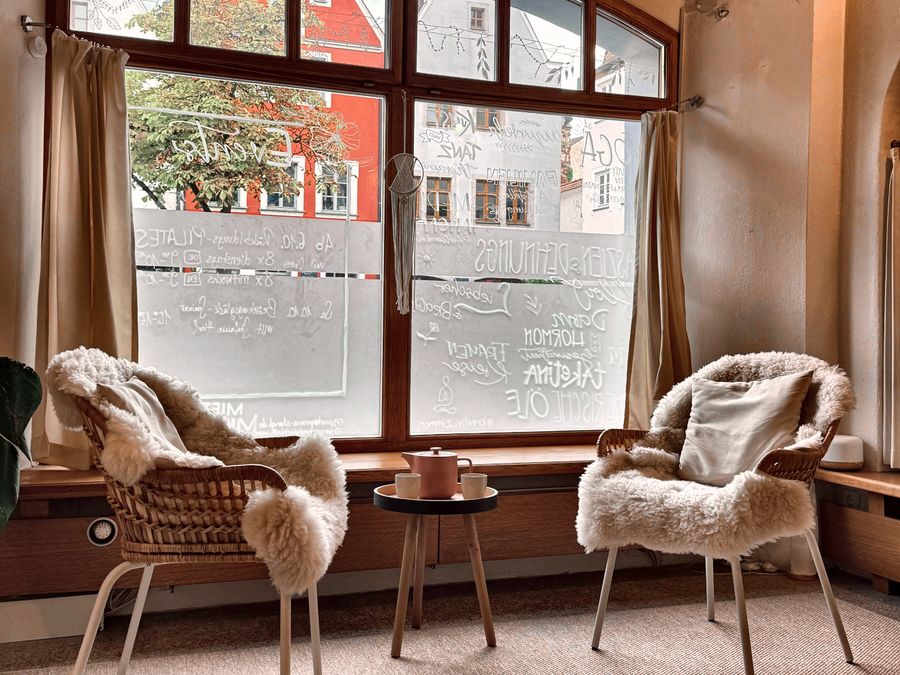 Zwei Sessel mit Schaffellen am Fenster, dazwischen ein kleiner Tisch mit Teekanne und zwei Tassen